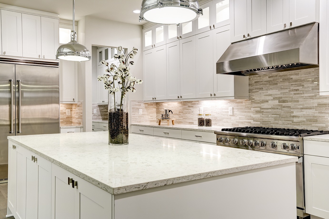 Gourmet kitchen features white shaker cabinets with marble countertops, stone subway tile backsplash, double door stainless steel refrigerator and gorgeous kitchen island.