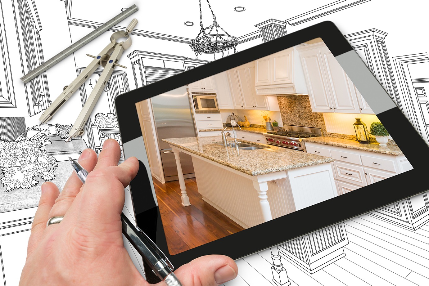 Hand of Architect on Computer Tablet Showing Photo of Kitchen Drawing Behind with Compass and Ruler.