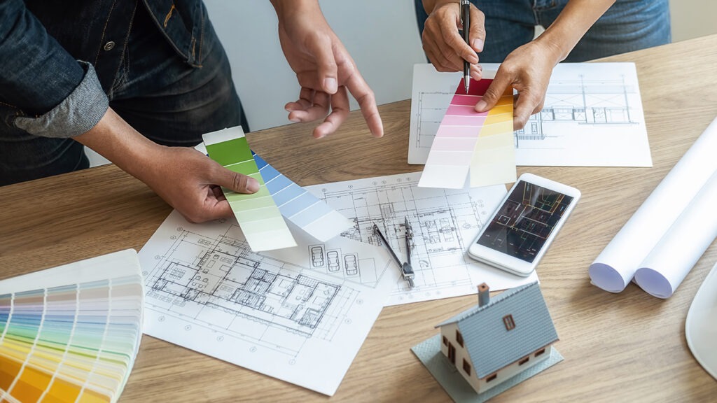 Interior designer and Architect choosing color in color swatch samples chart for house coloring selection in office with blueprint. Construction concept.
