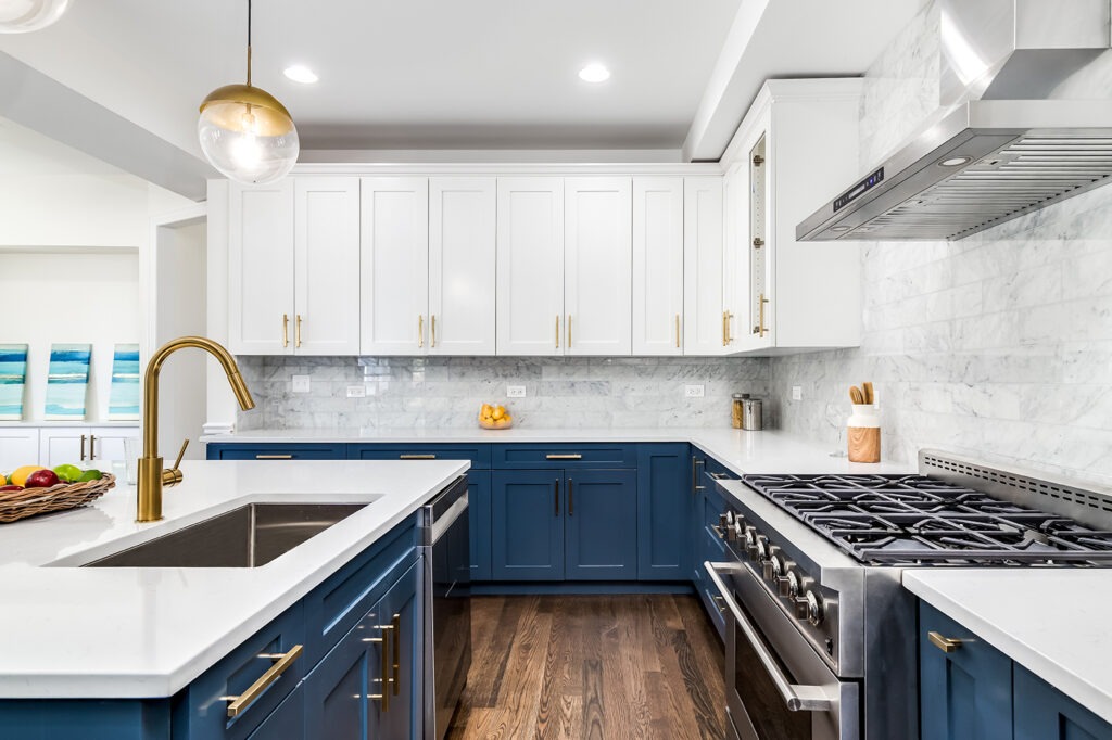 A luxurious white and blue kitchen with gold hardware, Bosch and Samsung stainless steel appliances, and white marbled granite counter tops.