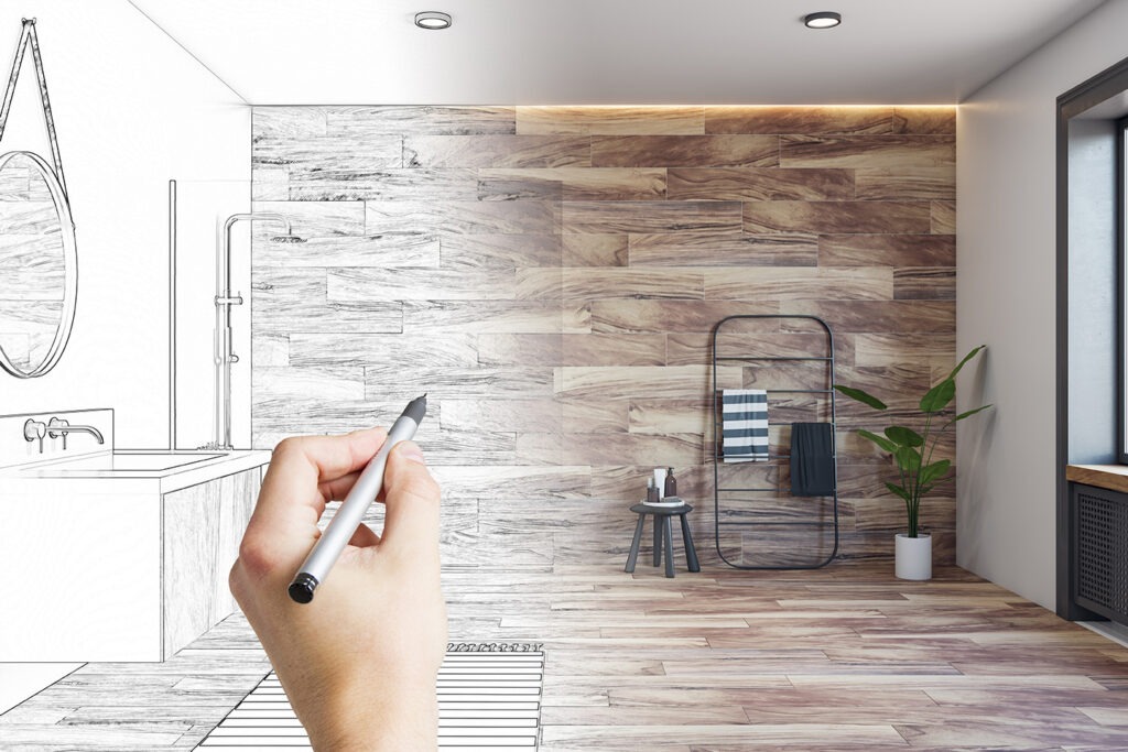 Human hand with pencil making design project of modern bathroom with stylish shower area, towel holder and green plant on wood effect tiles wall background