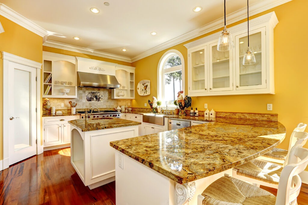 Bright yellow kitchen interior in luxury house with granite tops and kitchen island.