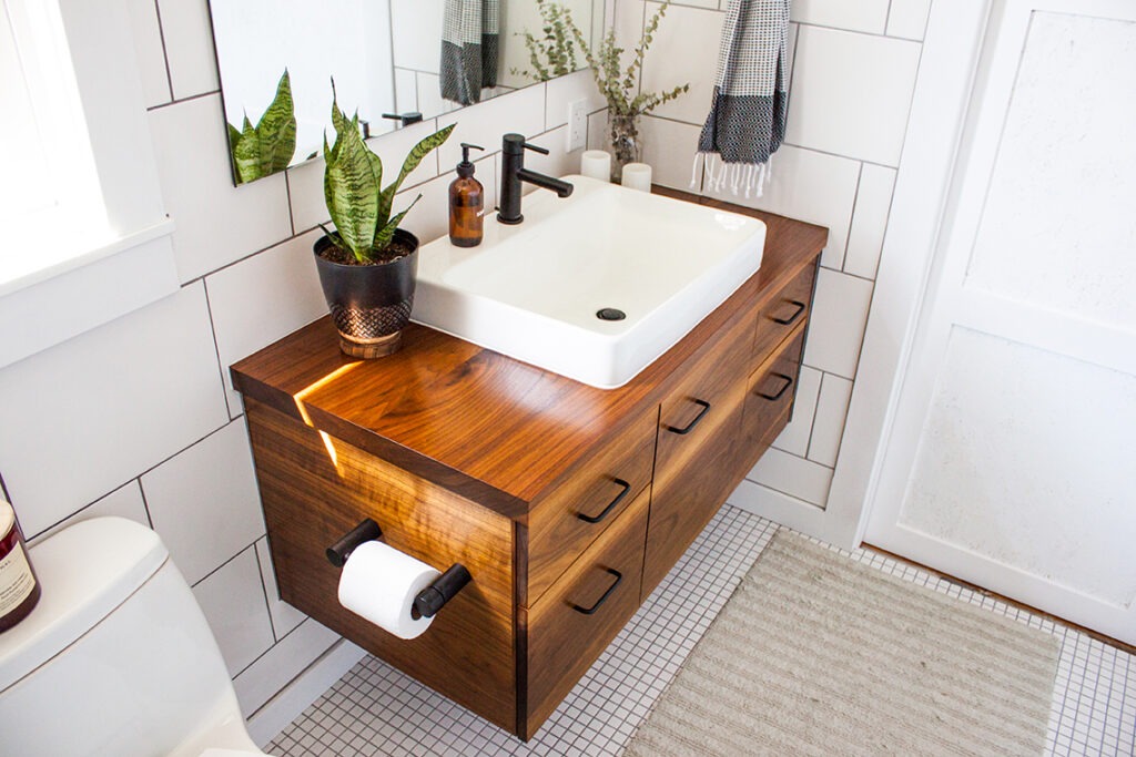 Modern decorated bathroom vanity in a modern white bathroom with natural light and plants.