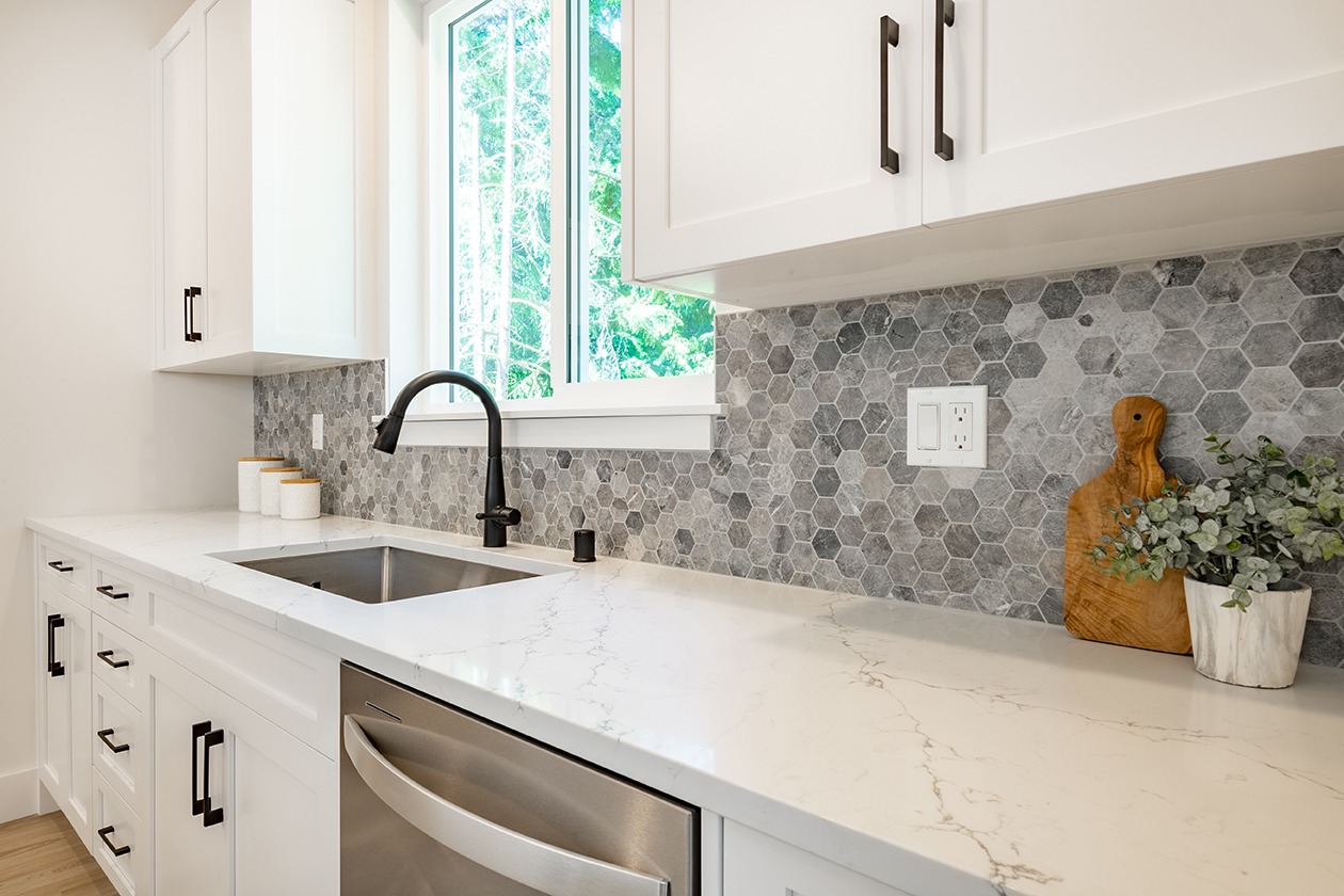 white kitchen with stools tile backsplash chefs island stainless appliances wood floor