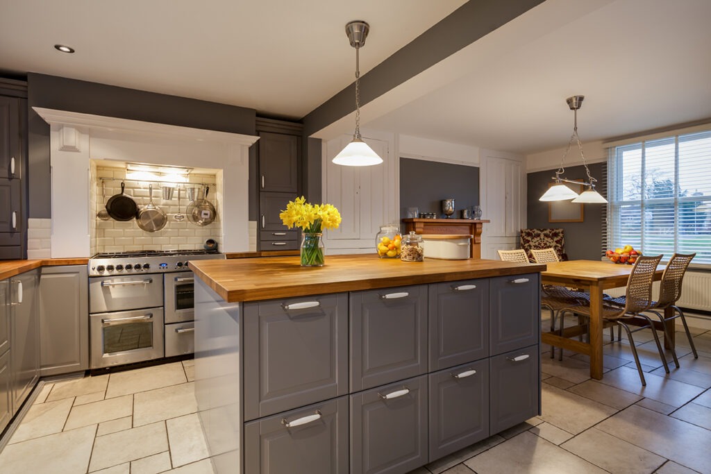 Modern kitchen with traditional looking built in cabinets in grey and white with built in range style oven and breakfast area with table and chairs